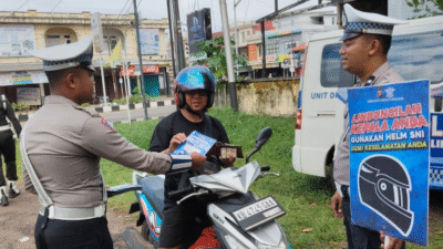 Petugas Satlantas Polres Ketapang memeriksa surat kelengkapan pengendara sambil membawa papan himbauan keselamatan wajib helm SNI dalam Operasi Zebra Kapuas. (Dok. HO/Faktakalbar.id)