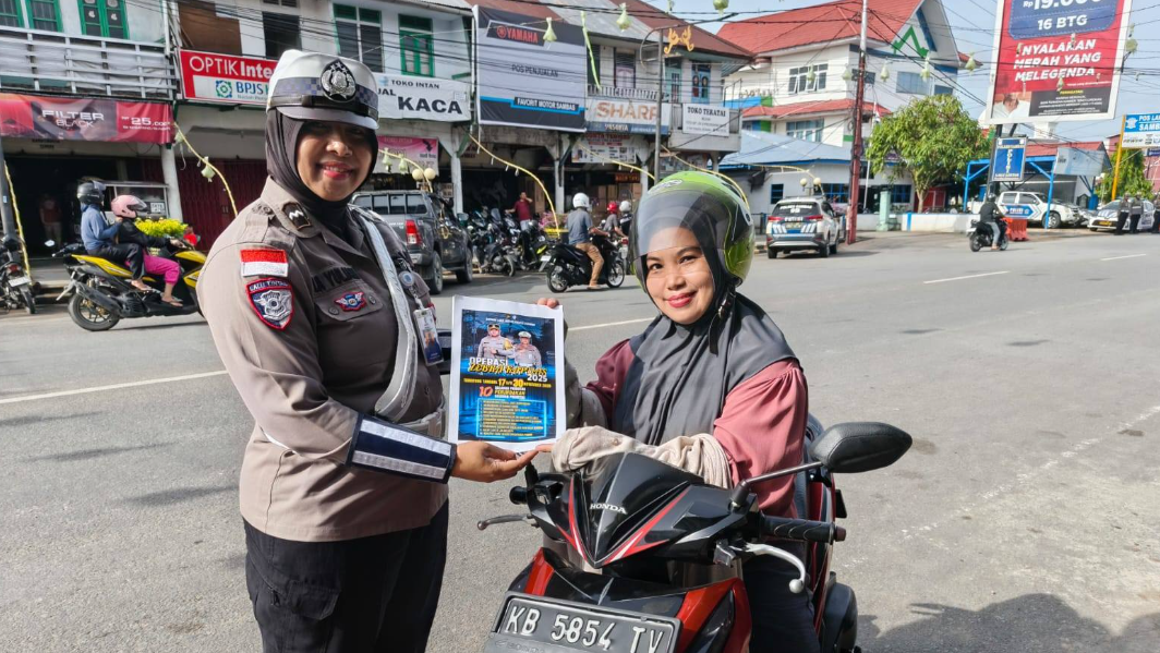Personel Polwan Satlantas Polres Sambas memberikan brosur sosialisasi Operasi Zebra Kapuas 2025 kepada pengendara motor wanita di jalan raya. (Dok. HO/Faktakalbar.id)