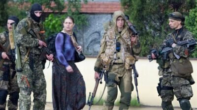 Sosok Olga Kulygina (tengah, rok panjang) tertangkap kamera sedang memegang senapan serbu AKS-74 di tengah pasukan milisi di Sloviansk, Ukraina, Mei 2014. Di balik penampilannya sebagai akademisi, ia adalah agen intelijen kunci Rusia. (Dok. Ist)