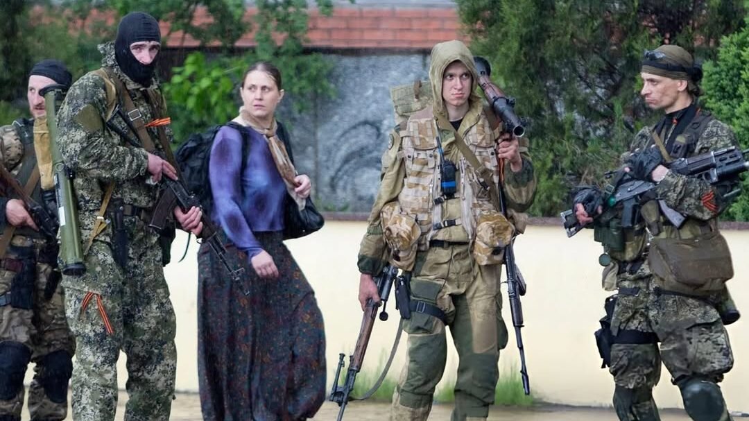 Sosok Olga Kulygina (tengah, rok panjang) tertangkap kamera sedang memegang senapan serbu AKS-74 di tengah pasukan milisi di Sloviansk, Ukraina, Mei 2014. Di balik penampilannya sebagai akademisi, ia adalah agen intelijen kunci Rusia. (Dok. Ist)