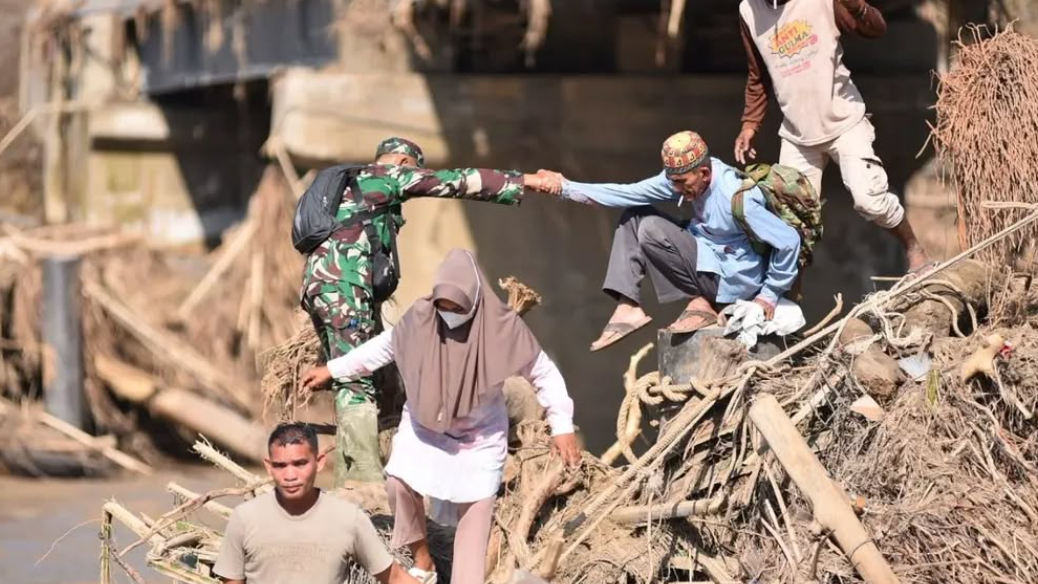 Prajurit Kodim 0111/Bireuen membantu warga menyeberangi sungai dengan tali dan jembatan darurat pasca banjir di Kecamatan Peusangan Selatan. (Dok. Puspen TNI)
