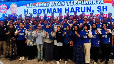 Boyman Harun dan puluhan pengurus PBVSI mengenakan seragam biru berpose mengepalkan tangan di depan panggung Musprov dengan banner ucapan selamat. (Dok. HO/Faktakalbar.id)