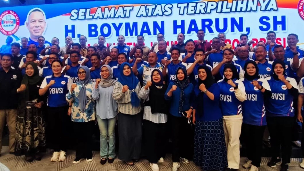 Boyman Harun dan puluhan pengurus PBVSI mengenakan seragam biru berpose mengepalkan tangan di depan panggung Musprov dengan banner ucapan selamat. (Dok. HO/Faktakalbar.id)