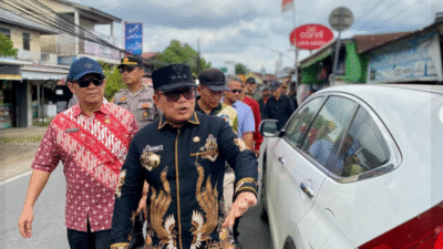 Bupati Sujiwo mengenakan kemeja batik hitam dan kacamata hitam berjalan kaki memantau deretan ruko di pinggir jalan raya yang padat. (Dok. HO/Faktakalbar.id)