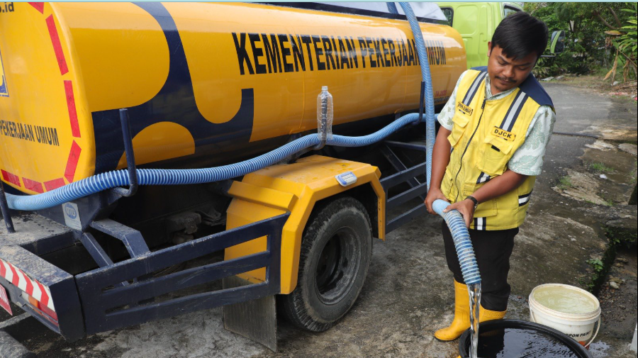Petugas berseragam kuning dari Dinas Pekerjaan Umum mengisi ember warga dengan air bersih melalui selang dari truk tangki air berwarna kuning. (Dok. BNPB)