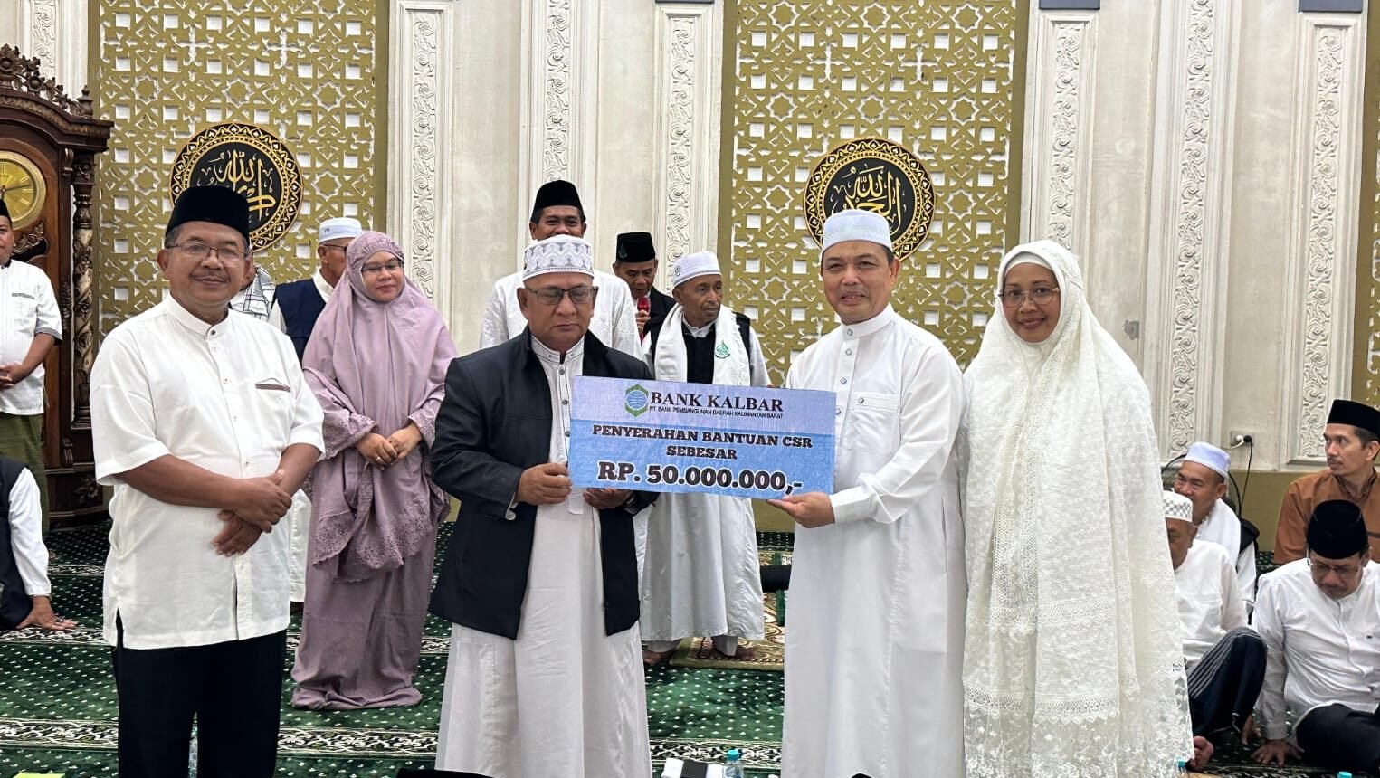 Gubernur Ria Norsan saat menyerahkan bantuan dana hibah dan perlengkapan ibadah secara simbolis kepada pengurus masjid di Kecamatan Tebas, Kabupaten Sambas, Jumat (27/12/2025).