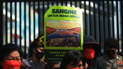 Massa aksi memegang poster bertuliskan "Sangihe Untuk Masa Depan" dan menolak kehadiran perusahaan tambang dengan latar belakang barikade polisi. (Dok. Ist)