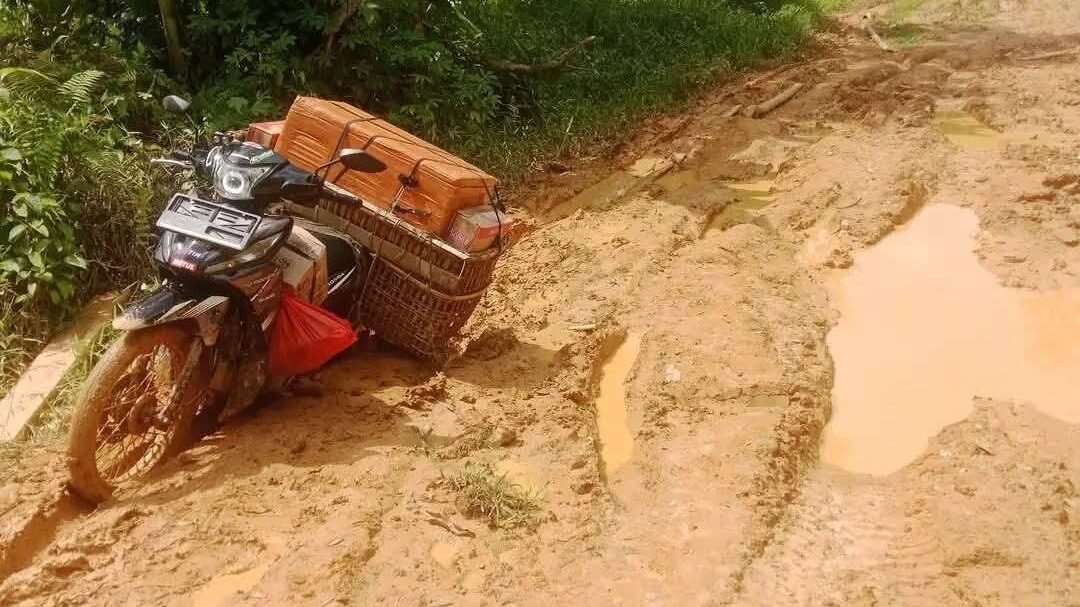 Sebuah sepeda motor yang membawa muatan barang tampak kesulitan melintasi Jalan Inggar, Kecamatan Kayan Hilir, Kabupaten Sintang, yang kondisinya rusak parah dan dipenuhi lumpur tebal.