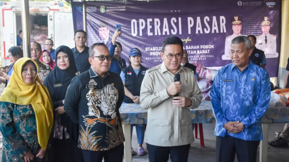 Menteri Perdagangan Budi Santoso memegang mikrofon berbicara di depan spanduk operasi pasar didampingi Bupati Sujiwo dan pejabat terkait. (Dok. HO/Faktakalbar.id)