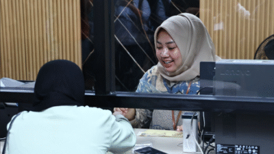 Seorang petugas wanita berhijab tersenyum melayani warga di balik loket kaca Mal Pelayanan Publik Pontianak. (Dok. HO/Faktakalbar.id)