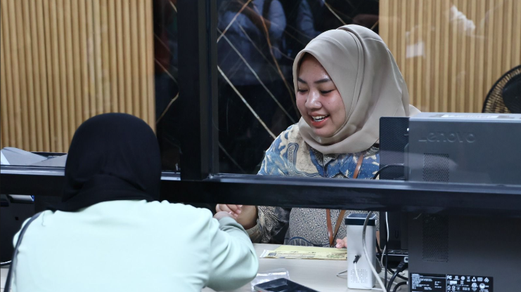 Seorang petugas wanita berhijab tersenyum melayani warga di balik loket kaca Mal Pelayanan Publik Pontianak. (Dok. HO/Faktakalbar.id)