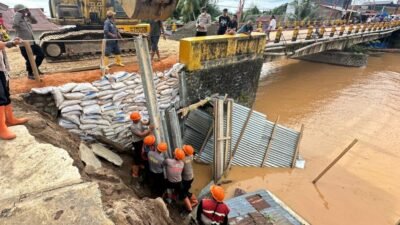 Personel SAR Batalyon A Sat Brimob Polda Sumut bersama warga saat melakukan pengerjaan darurat penimbunan Jembatan Halangan, Kecamatan Pandan, untuk memulihkan akses transportasi.