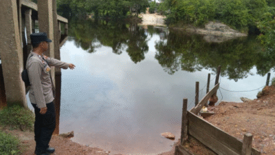Anggota polisi menunjuk ke arah permukaan sungai yang mulai naik saat melakukan patroli rawan banjir dan bencana di wilayah Jangkang. (Dok. HO/Faktakalbar.id)