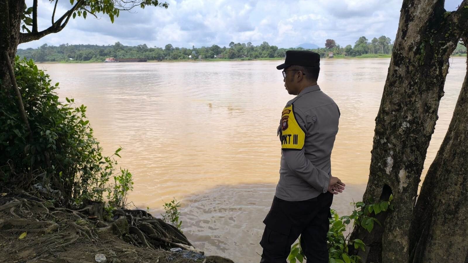 Personel Polsek Meliau saat melakukan pemantauan kondisi debit air di tepian Sungai Kapuas, Kecamatan Meliau, Kabupaten Sanggau, Jumat (5/12/2025).