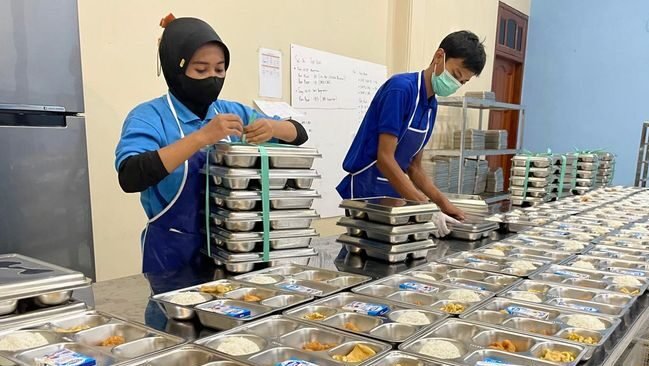 Proses pengemasan menu Makan Bergizi Gratis (MBG) siap santap yang lengkap dengan nasi, lauk pauk, dan susu. Selama libur, BGN juga menyiapkan opsi menu bahan kering untuk siswa (Dok. Ist)