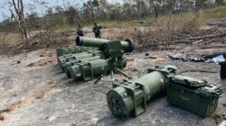 Tumpukan tabung rudal berwarna hijau dan perangkat pembidik canggih tergeletak di tanah berbatu dengan latar belakang tentara berseragam loreng sedang berjaga. (Dok. Ist)