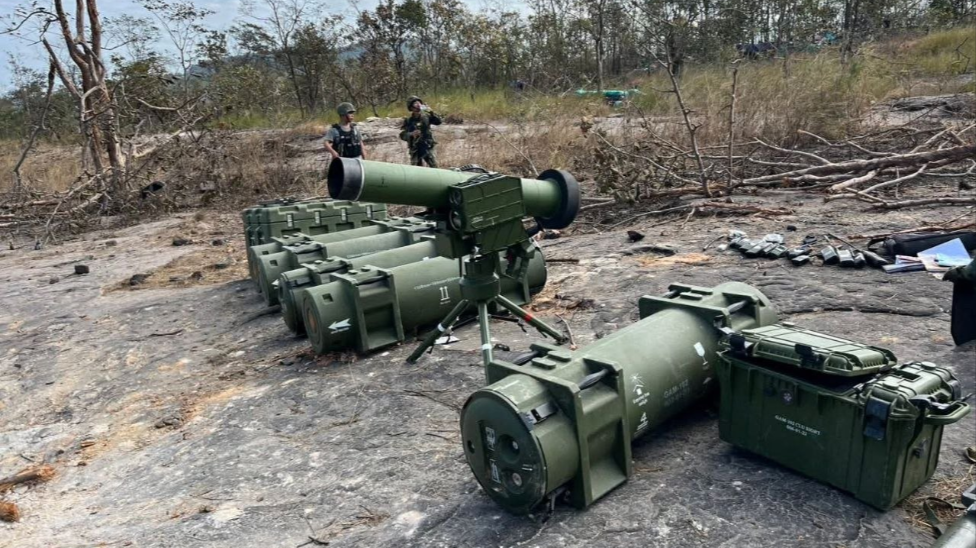 Tumpukan tabung rudal berwarna hijau dan perangkat pembidik canggih tergeletak di tanah berbatu dengan latar belakang tentara berseragam loreng sedang berjaga. (Dok. Ist)