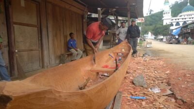 Salihin, warga Kampung Toweren Owaq, Aceh Tengah, sedang memahat kayu gelondongan sisa banjir bandang untuk dijadikan sampan sebagai sarana mencari nafkah di danau, Sabtu (27/12). (Dok. CNN)