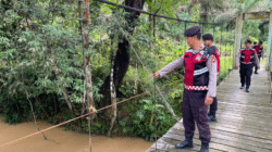 Personel Sat Samapta Polres Bengkayang memantau debit air sungai dan kondisi tebing rawan longsor di Kecamatan Lumar sebagai antisipasi bencana. (Dok. HO/Faktakalbar.id)