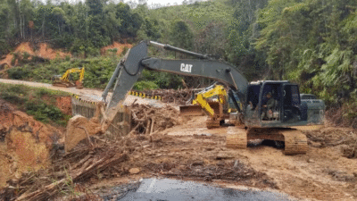 Dua unit ekskavator TNI AD sedang mengeruk tanah lumpur dan puing kayu di jalanan rusak akibat longsor di daerah perbukitan. (Dok. BNPB)