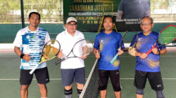 Four male tennis players wearing sports attire holding rackets pose together by the net on a green hard court. (Dok. HO./Faktakalbar.id)