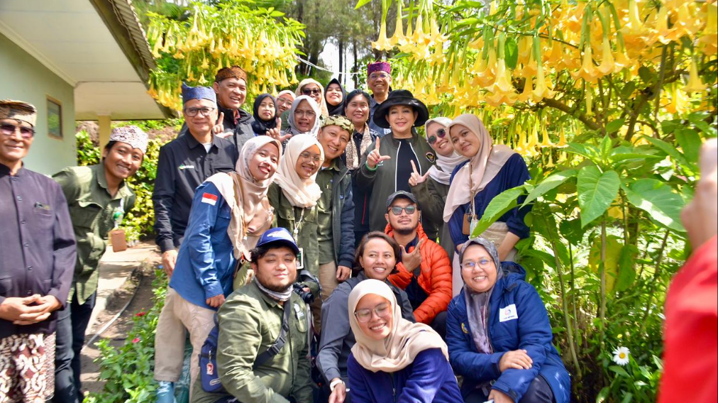 Titiek Soeharto mengenakan topi rimba hitam dan jaket hitam tersenyum berfoto wefie bersama warga dan staf di taman bunga berlatar dataran tinggi. (Dok. HO/Faktakalbar.id)