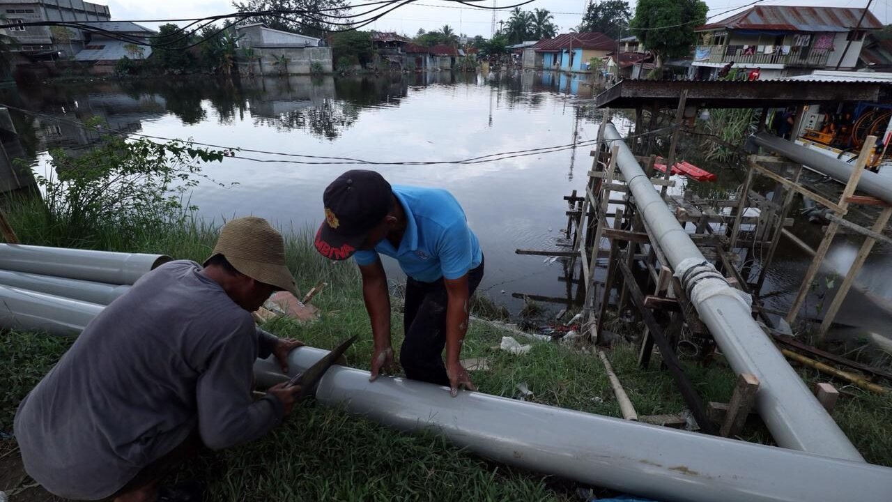 Sejumlah petugas dari BPBD Kabupaten Langkat, BBWS Sumatra Utara II dan warga berupaya mengoperasikan pompa air untuk menguras genangan banjir yang menggenangi wilayah Tanjung Pura, Kabupaten Langkat, Sumatra Utara, Jumat (12/12).