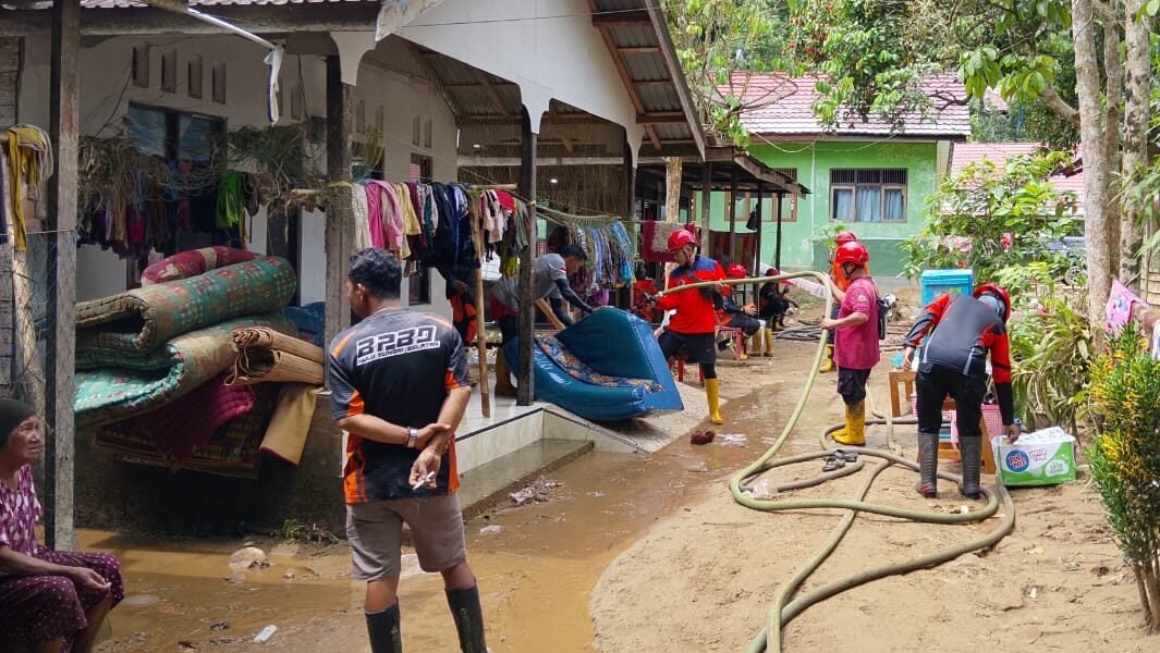 Warga dibantu petugas gabungan saat membersihkan sisa lumpur dan material sampah pasca banjir yang melanda pemukiman di Kalimantan Selatan, Minggu (28/12).