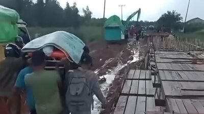 Warga terpaksa menggotong keranda jenazah melewati jalan berlumpur pekat di kawasan Sungai Melayu Rayak, Ketapang, akibat antrean kendaraan yang panjang dan kondisi jalan rusak, Senin (30/12/2025). (Dok. Ist)