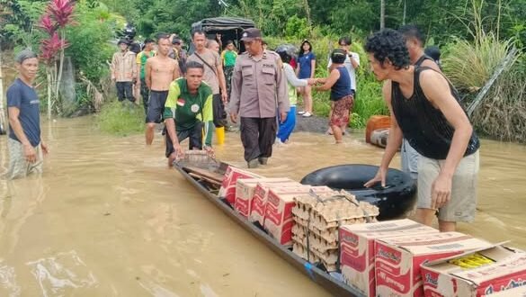 Personel kepolisian saat menyalurkan bantuan logistik kepada warga yang terdampak banjir akibat luapan Sungai Sekayam di Kecamatan Entikong, Jumat (9/1).