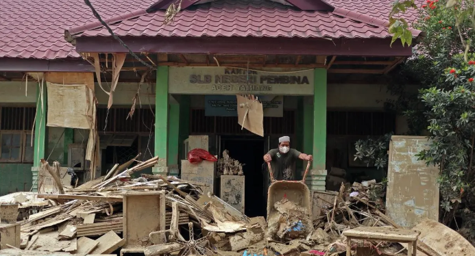 Sejumlah relawan dan guru membersihkan lumpur dan puing sisa banjir di Sekolah Luar Biasa (SLB) Negeri Pembina Aceh Tamiang, Selasa (13/1).