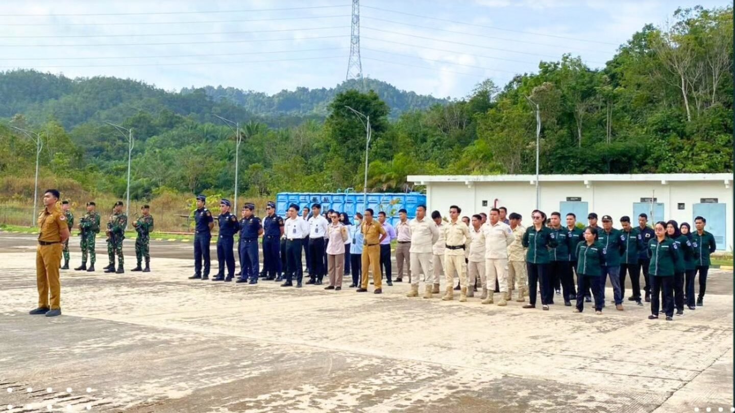 Suasana apel bersama personel gabungan dari berbagai instansi berbaris rapi di halaman PLBN Jagoi Babang dengan latar belakang pemandangan bukit dan langit cerah. (Dok. HO/Faktakalbar.id)