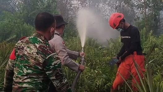 Bhabinkamtibmas Batulayang, Aipda Roni, bersama tim gabungan saat berjibaku memadamkan api di lahan gambut kawasan Gang Flora, Pontianak Utara, Selasa (27/1).
