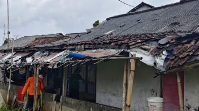 Petugas BPBD bersama warga saat melakukan pembersihan puing bangunan dan material pohon tumbang akibat angin kencang di wilayah Kabupaten Bogor.