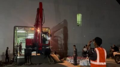 Proses penurunan alat berat ekskavator dari lambung KRI Banda Aceh-593 di Dermaga Krueng Geukeuh, Lhokseumawe pada malam hari. (Dok. Puspen TNI)