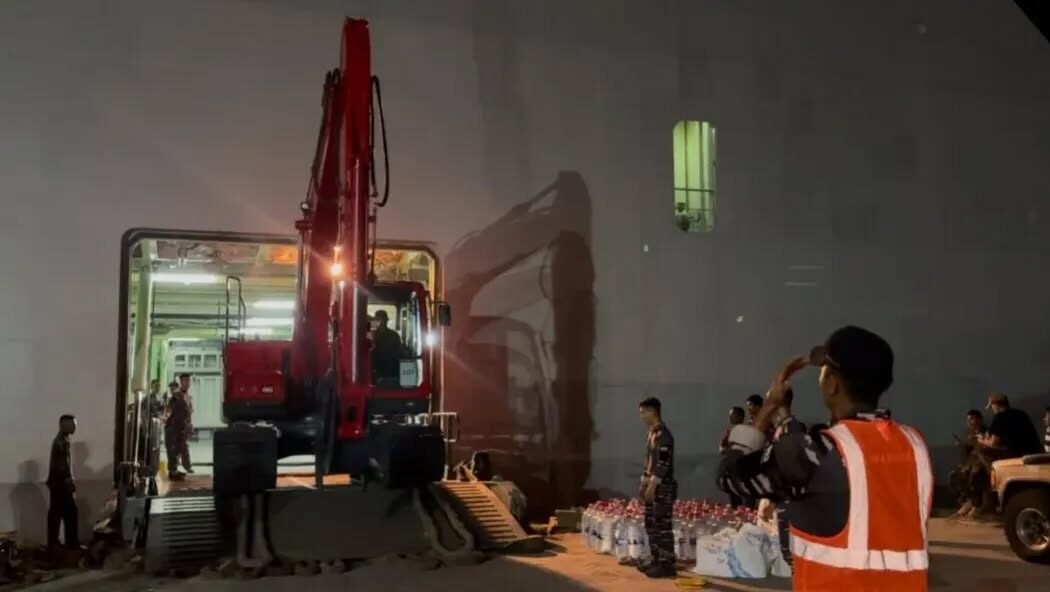 Proses penurunan alat berat ekskavator dari lambung KRI Banda Aceh-593 di Dermaga Krueng Geukeuh, Lhokseumawe pada malam hari. (Dok. Puspen TNI)