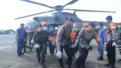 Personel TNI AU dan tim SAR gabungan menandu kantong jenazah berisi bagian tubuh korban pesawat ATR 42-500 turun dari helikopter Caracal di apron Lanud Sultan Hasanuddin. (Dok. HO/Faktakalbar.id)