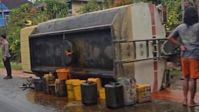 Personel kepolisian mengatur lalu lintas di dekat truk CPO yang terguling di kawasan Tanjung Kapuas, Sanggau. Tumpahan minyak membuat jalanan menjadi licin, Minggu (11/1).