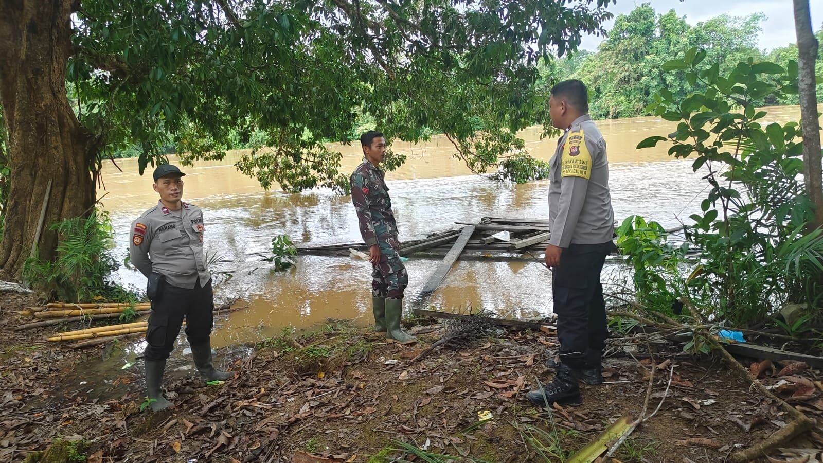 Personel Polsek dan Koramil Sekadau Hilir memantau kenaikan debit air di tepian Sungai Sekadau, Desa Mungguk. (Dok. HO/Faktakalbar.id)