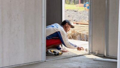 Seorang pekerja bangunan sedang menyelesaikan pemasangan kerangka pintu dan lantai pada salah satu unit hunian sementara (huntara) di Aceh Tamiang. (Dok. HO/Faktakalbar.id)