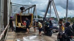 Petugas Damkar dibantu kepolisian saat melakukan penyemprotan air untuk membersihkan sisa tumpahan solar yang menyebabkan jalan licin dan pengendara terjatuh di Jembatan Melawi, Sabtu (3/1).