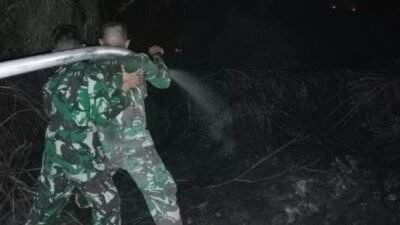 Personel Denmadam XII/Tanjungpura saat memadamkan api yang membakar lahan gambut di dekat pemukiman warga, Minggu (18/1) dini hari.