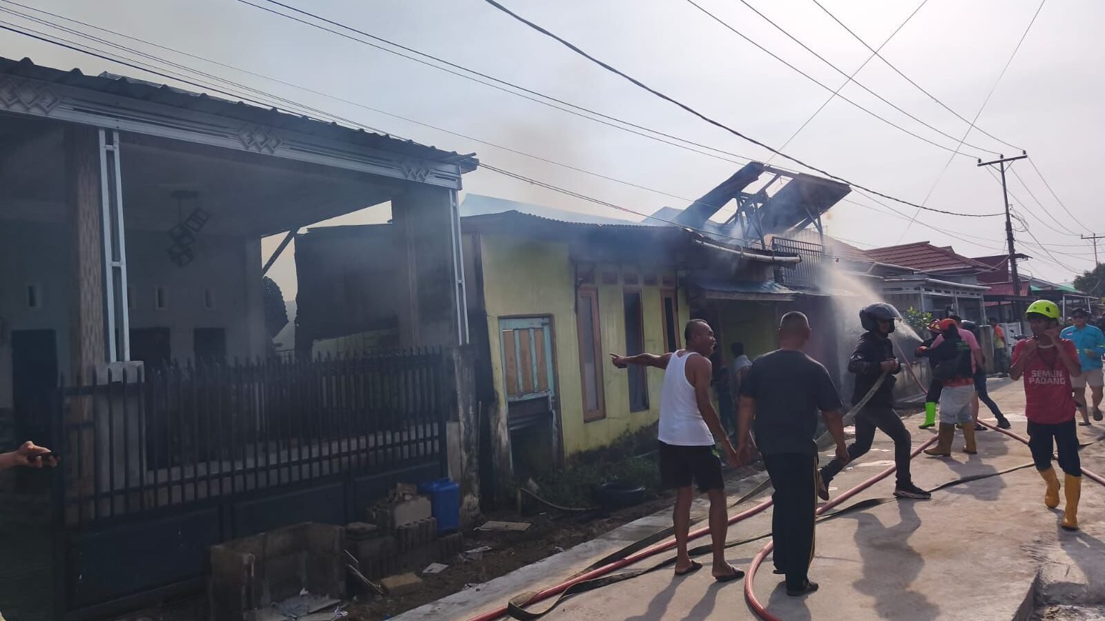 Petugas pemadam kebakaran gabungan saat melakukan proses pendinginan dan pemeriksaan di lokasi kebakaran rumah Komplek Bhayangkara Permai, Senin (26/1).