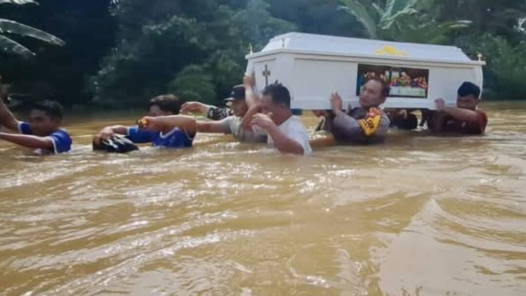 Personel Polsek Entikong bersama warga setempat saat menggotong peti jenazah menerobos banjir setinggi 1,5 meter akibat ambulans tidak dapat melintas di Kecamatan Beduai, Minggu (11/1).