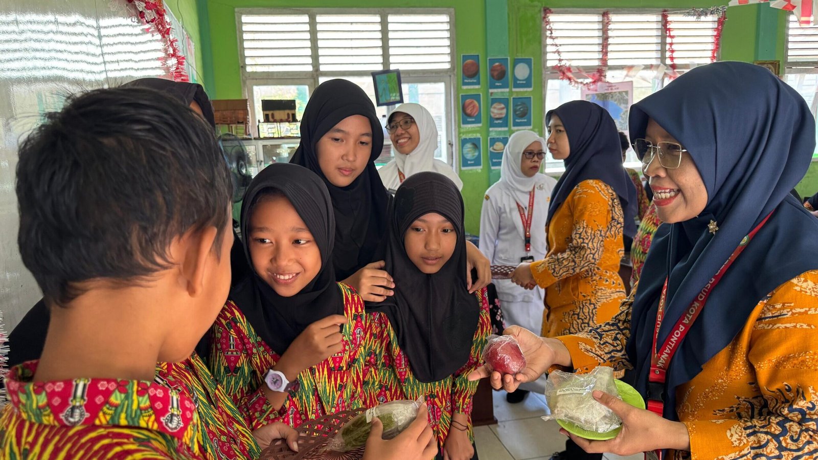 Petugas dari RSUD SSMA Pontianak berinteraksi dan membagikan buah kepada siswa SDN 74 Pontianak Barat dalam kegiatan edukasi gizi seimbang. (Dok. HO/Faktakalbar.id)