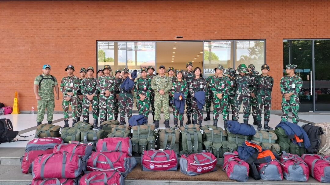 Sekelompok kadet mahasiswa UNHAN RI berseragam loreng lengkap dan perwira TNI berfoto bersama dengan tumpukan tas perlengkapan satgas berwarna merah dan hijau di depan lobi gedung kampus. (Dok. HO/Faktakalbar.id)