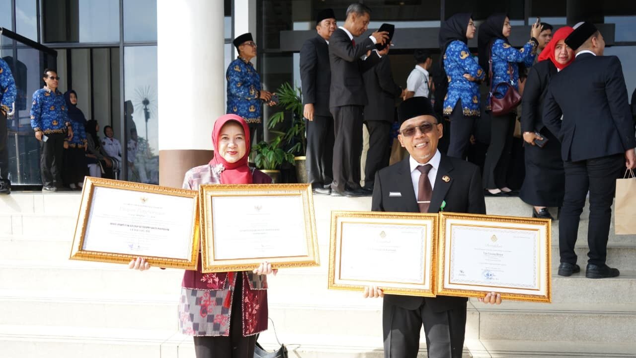 Sekretaris Daerah Kota Pontianak, Amirullah, bersama Kepala Dinas Perpustakaan dan Kearsipan, Rendrayani, memperlihatkan dua piagam penghargaan yang diraih pada HUT ke-69 Pemprov Kalbar. (Dok. HO/Faktakalbar.id)