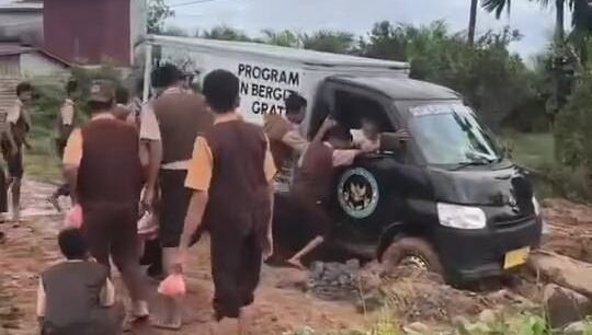 Sejumlah siswa di Kecamatan Seponti, Kabupaten Kayong Utara, bergotong royong mendorong mobil distribusi program MBG yang amblas di jalan berlumpur, Jumat (9/1).