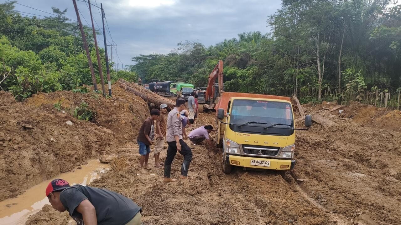 Personel kepolisian dan warga membantu evakuasi truk kuning yang terjebak lumpur di jalan rusak Desa Lembah Hijau Nanga Tayap Ketapang. (Dok. Ist)