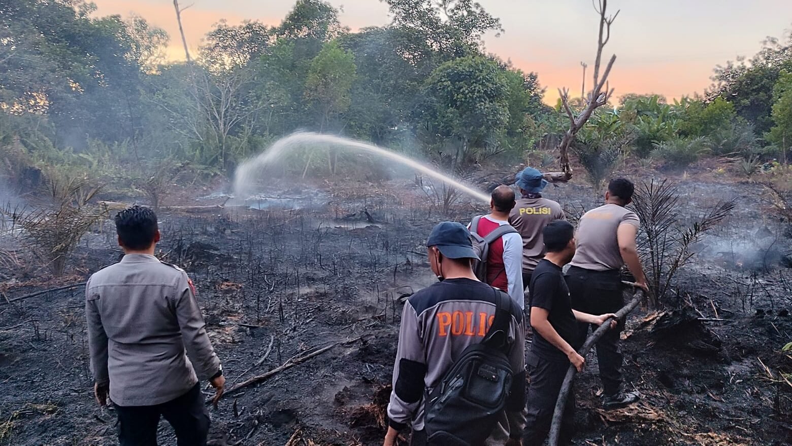 Petugas di lapangan berupaya memadamkan sisa api pada lahan gambut untuk mencegah kabut asap semakin meluas.